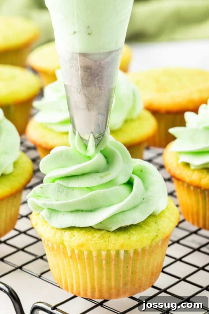 Close-up of piping light green lime frosting onto a coconut cupcake