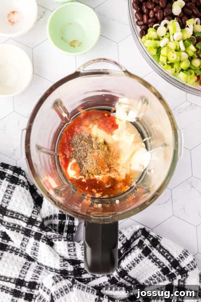 Blender filled with salad dressing ingredients before blending.