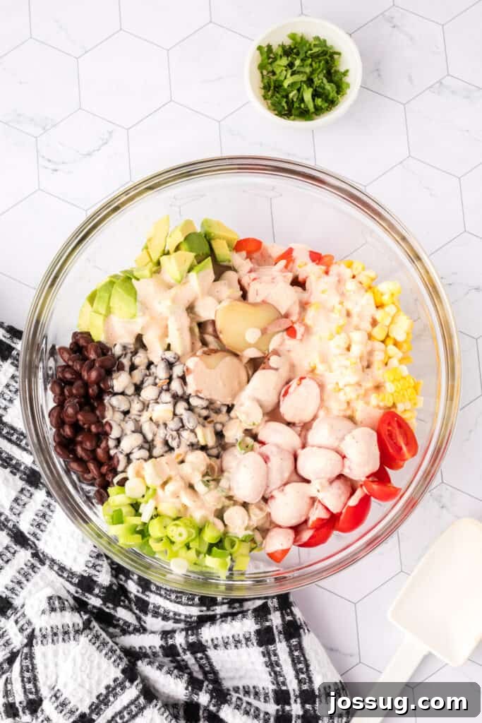 Southwest Potato Salad ingredients in a bowl with dressing poured over, ready to mix.