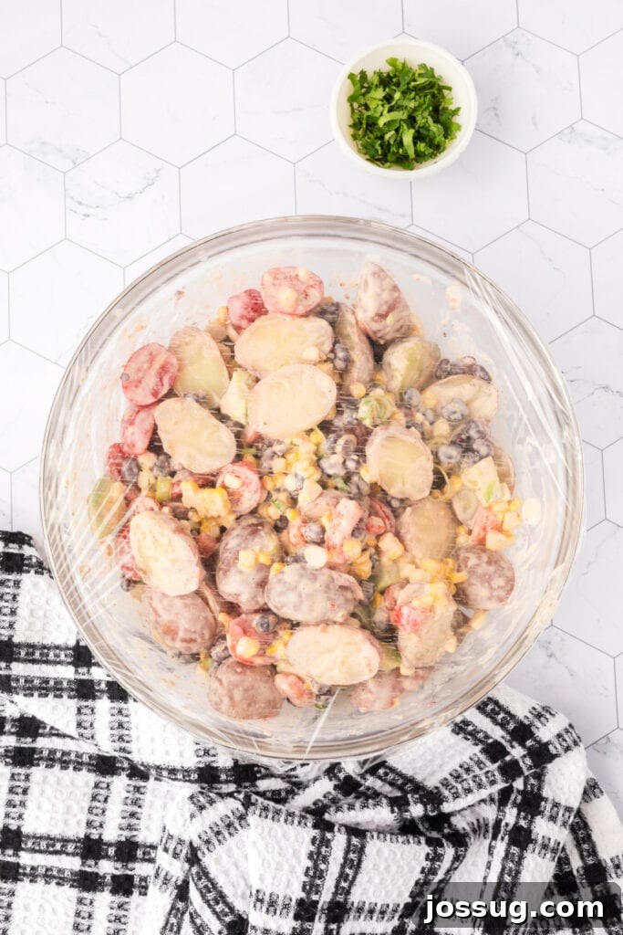 Southwest Potato Salad covered with plastic wrap, ready for chilling.