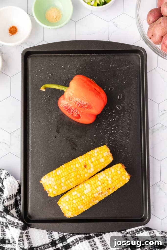 Roasted red bell pepper and charred corn on a black grill.