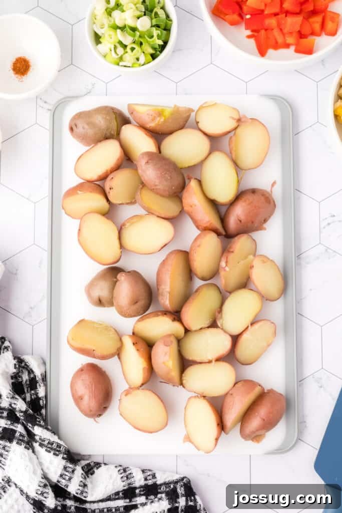 Halved cooked red potatoes arranged on a white cutting board.