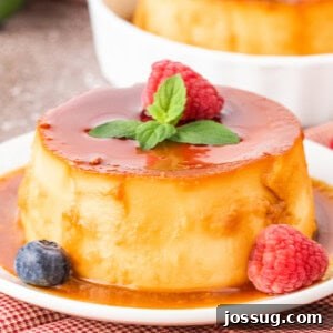 Close-up of mini caramel flan with caramel sauce, garnished with raspberry, mint, and a blueberry.