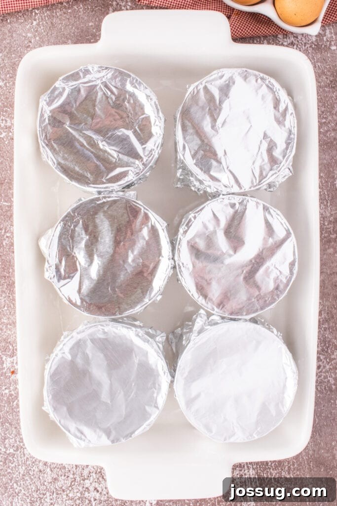 Caramel Flan Bites 9 Ramekins covered with foil placed in a large baking dish for a water bath.