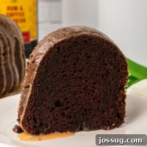 Close-up of a single slice of Chocolate Kahlua Bundt Cake on a white plate, showcasing its moist texture and rich glaze.
