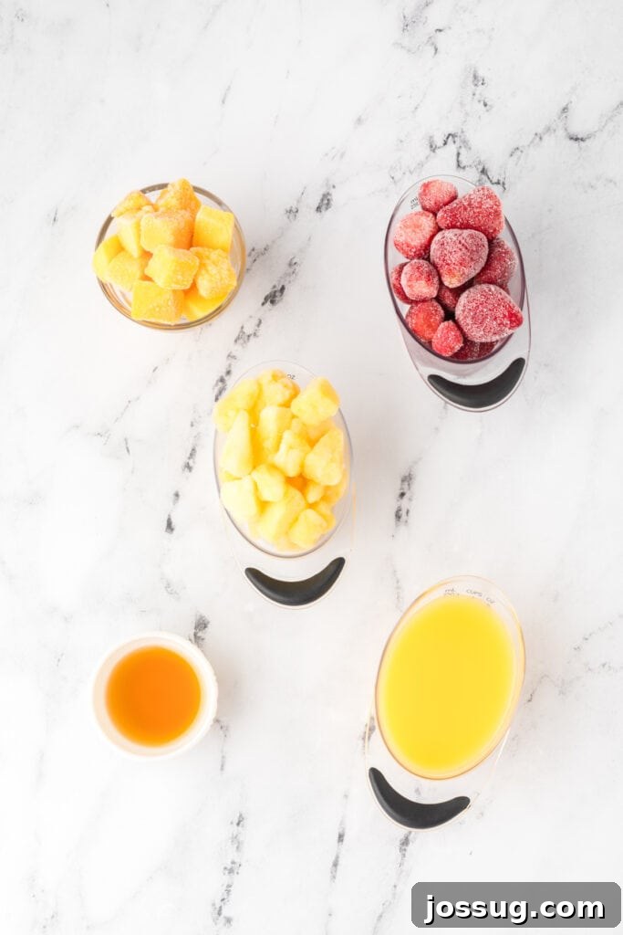 Tropical Ombre Smoothie 3 Measured ingredients for the sunrise sunset smoothie laid out on a marble background, including frozen fruit and orange juice.