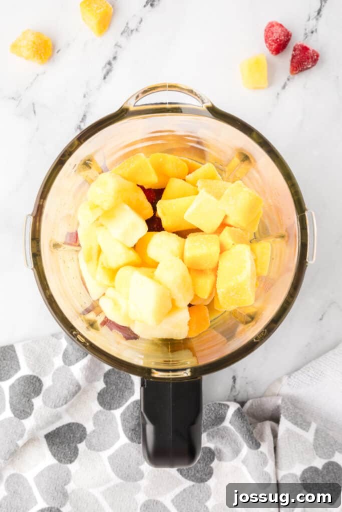 Tropical Ombre Smoothie 4 Frozen fruit and orange juice being added to a blender for a sunrise sunset smoothie.