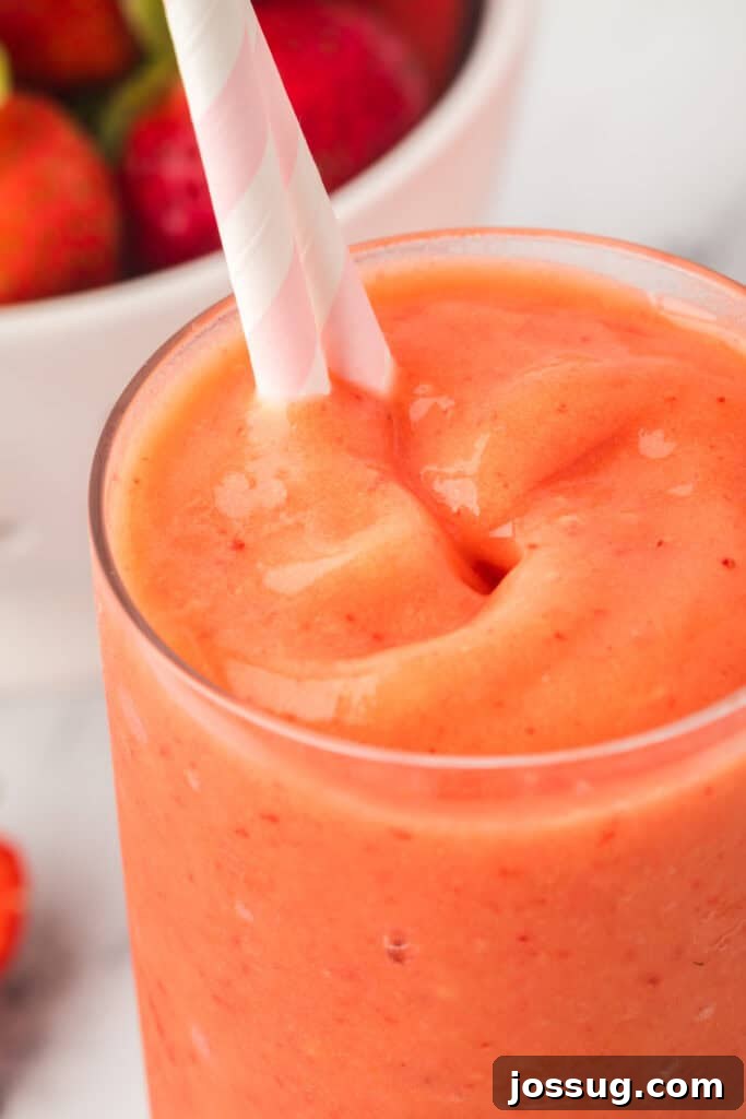 Tropical Ombre Smoothie 7 Close-up of a refreshing sunrise sunset smoothie with a striped straw, showing off its vibrant colors.