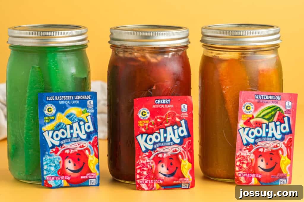 Sweet & Sour Zingers 12 Three glass jars of Kool-Aid pickles, each with a distinct color and flavor: vibrant blue raspberry, deep cherry red, and bright green watermelon.