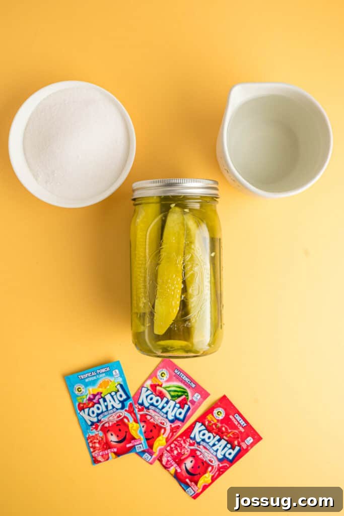 Sweet & Sour Zingers 3 Ingredients for Kool-Aid pickles laid out on a yellow background: a jar of pickle spears, packets of assorted Kool-Aid mixes, granulated sugar, and a glass of water.