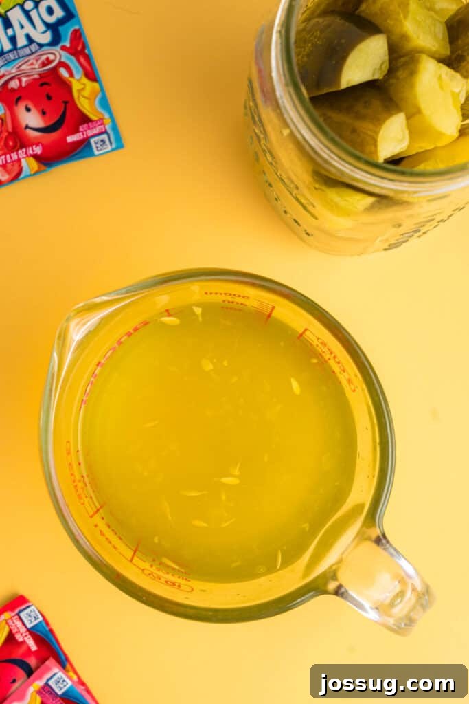 Sweet & Sour Zingers 4 Pickle brine being poured into a measuring cup, next to a jar of pickles and several Kool-Aid packets.