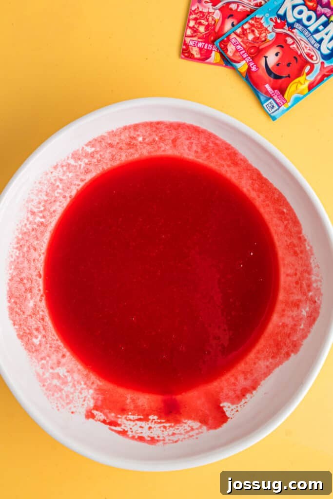 Sweet & Sour Zingers 7 A bowl filled with a brightly colored, fully combined red Kool-Aid mixture, ready for the next step.