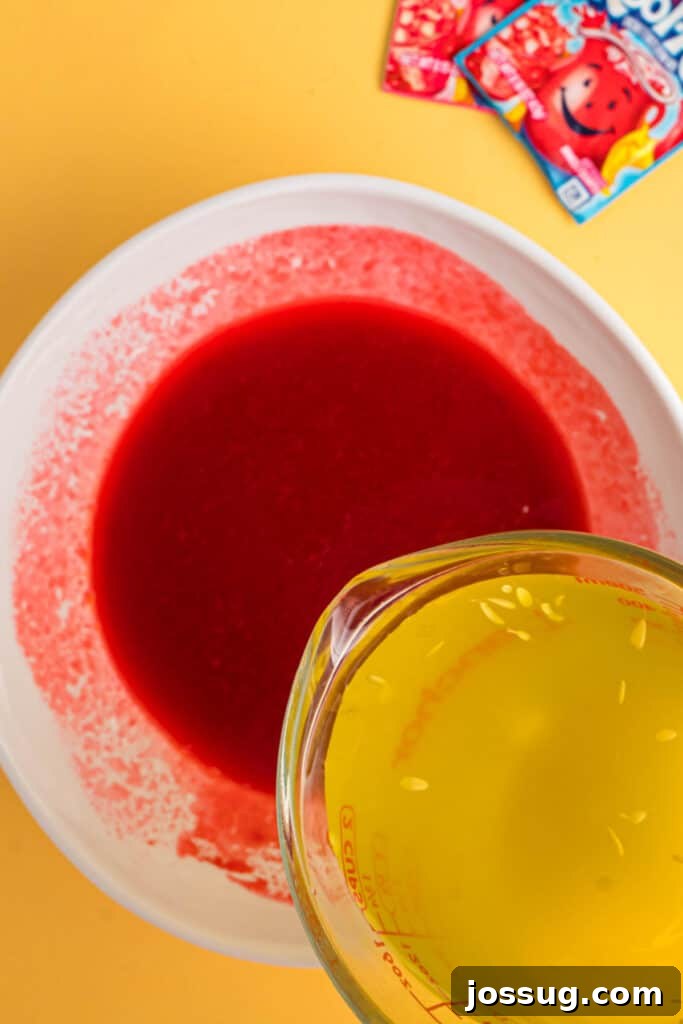 Sweet & Sour Zingers 8 Pickle brine being slowly poured into the vibrant red Kool-Aid mixture in a white bowl.