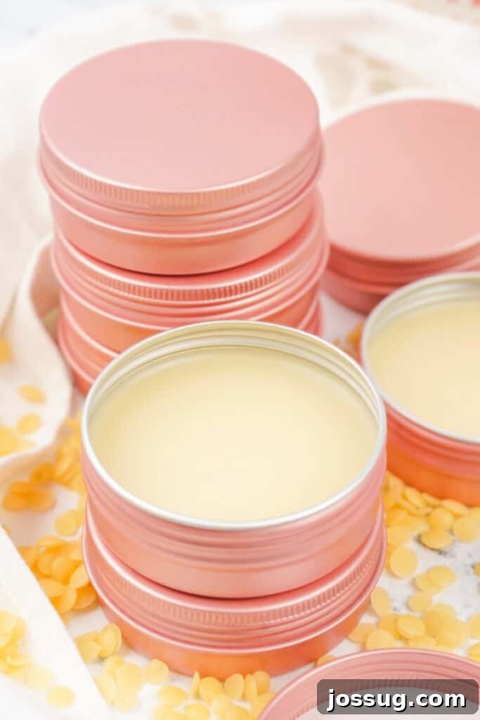 Happy Paws Balm 2 Stack of pink tins filled with finished dog paw balm, surrounded by beeswax pellets. Emphasizes natural ingredients and product presentation.