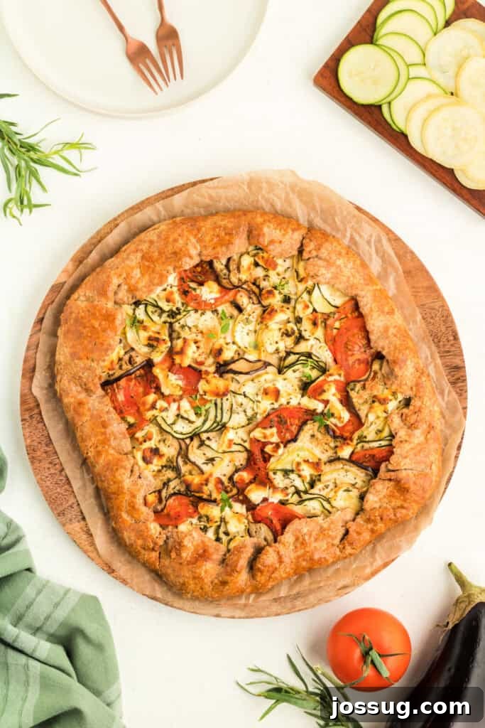 Fully baked summer vegetable galette on a wooden board with golden brown crust and colorful filling, ready to be served.
