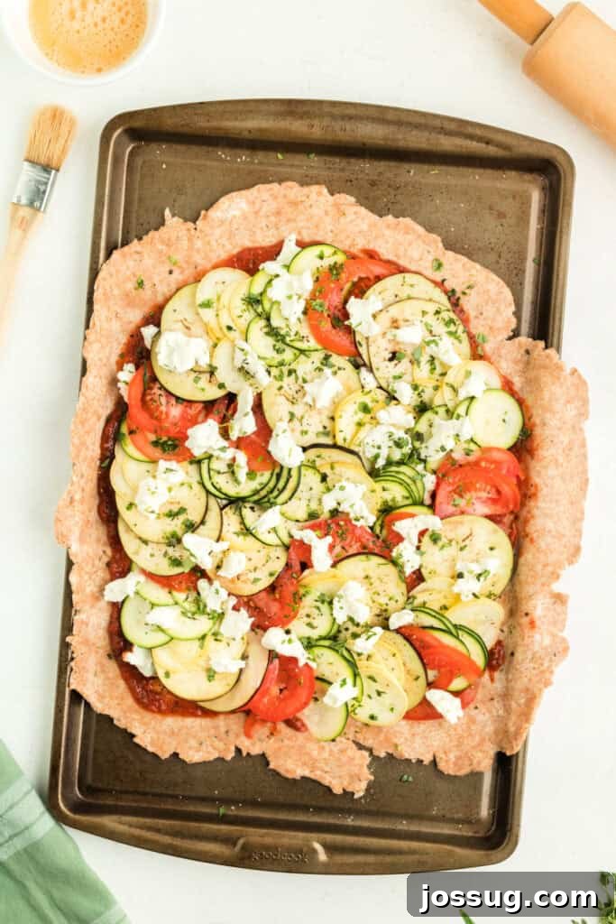 Assembled galette before baking, showcasing the vibrant vegetable filling, fresh herbs, goat cheese, and the beautifully folded, rustic crust edges, ready for the oven.