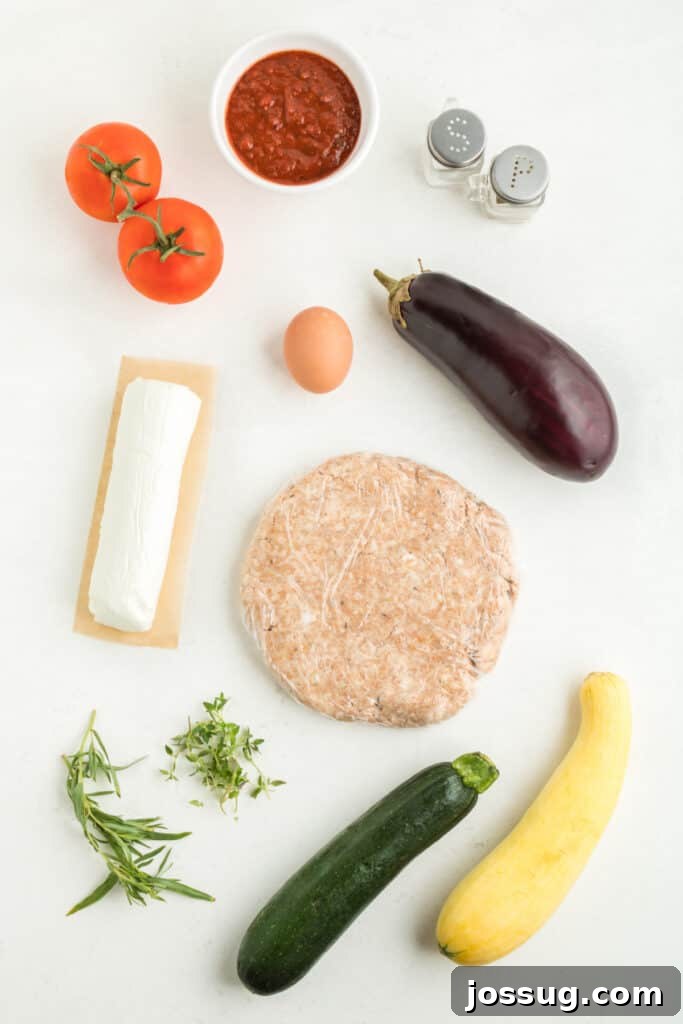 Fresh ingredients for the summer vegetable galette filling, including vibrant red tomatoes, green zucchini, purple eggplant, and creamy goat cheese on a wooden board.