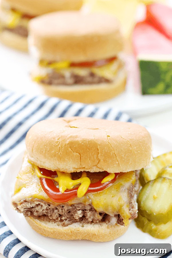 A perfectly cooked Easy Beef Slider, topped with melted cheddar cheese and a slice of dill pickle, presented on a crisp white plate.