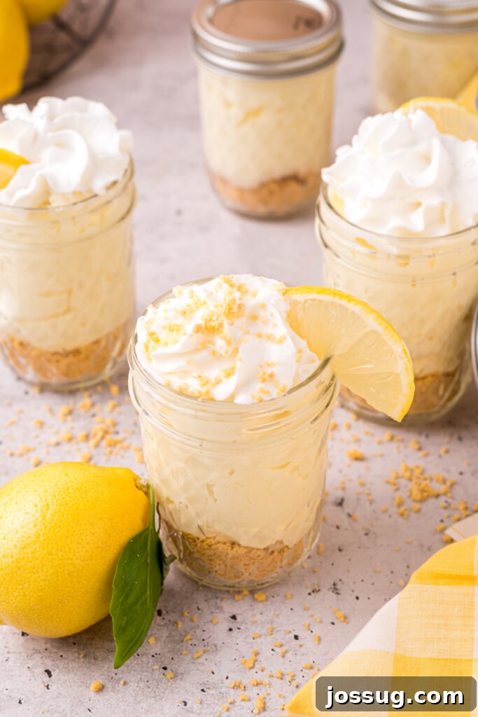 Zesty No-Bake Lemon Cheesecake Jars 4 Four mason jars neatly filled with layers of crushed cookies and creamy lemon cheesecake filling