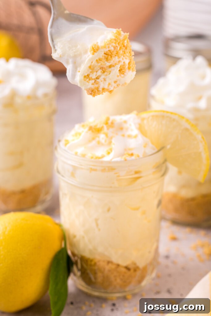 Zesty No-Bake Lemon Cheesecake Jars 5 A spoon scooping a generous portion of creamy lemon cheesecake from a jar