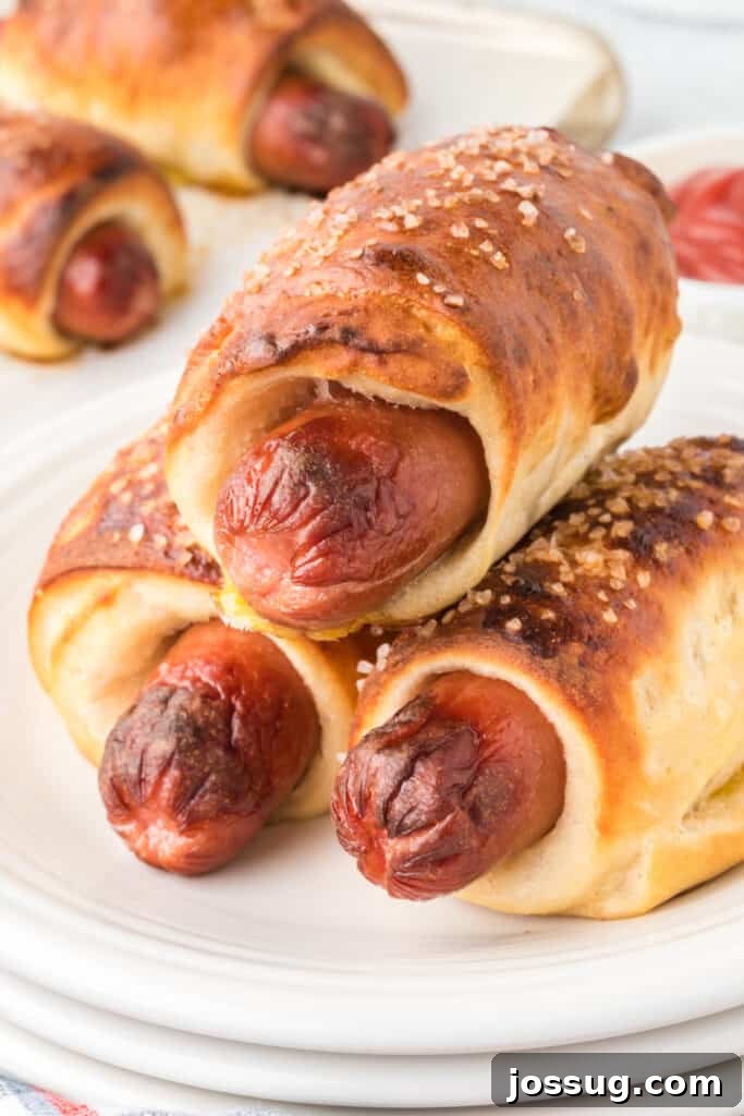 Homemade Pretzel Dogs in a Snap 2 Three golden brown pretzel dogs stacked on a plate, ready to be enjoyed.