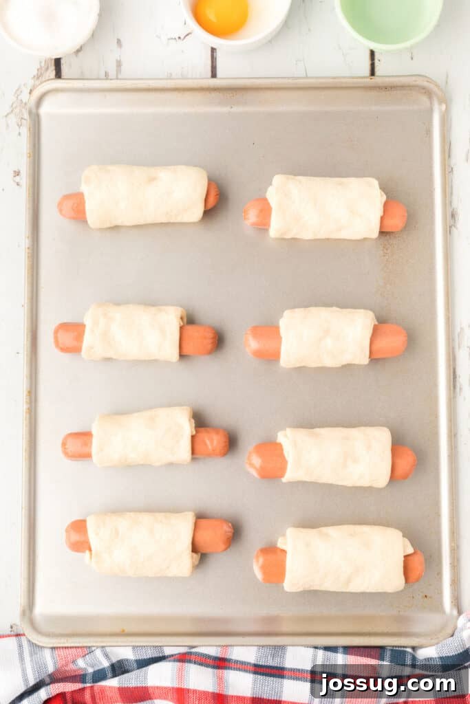 Homemade Pretzel Dogs in a Snap 6 Hot dogs being wrapped tightly in the prepared pizza dough sections.