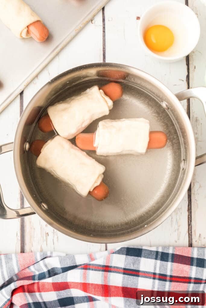 Homemade Pretzel Dogs in a Snap 7 Dough-wrapped hot dogs boiling in a pot of baking soda water.