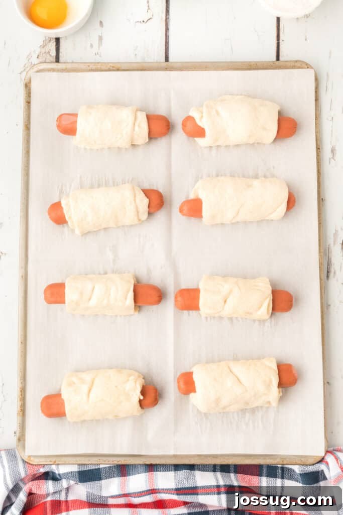 Homemade Pretzel Dogs in a Snap 8 Boiled pretzel dogs arranged on a parchment paper-lined baking sheet.