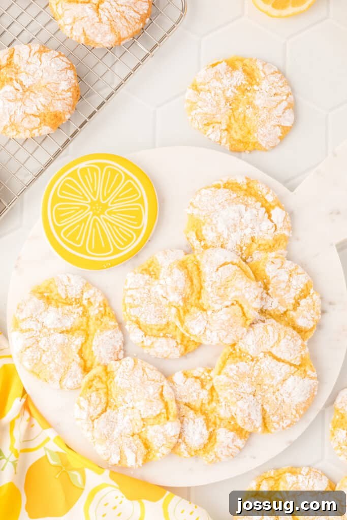 Sunshine Lemon Crinkles 2 Vibrant yellow Lemon Crinkle Cookies displayed on a pristine white plate, evoking a sense of fresh citrus and sunshine.
