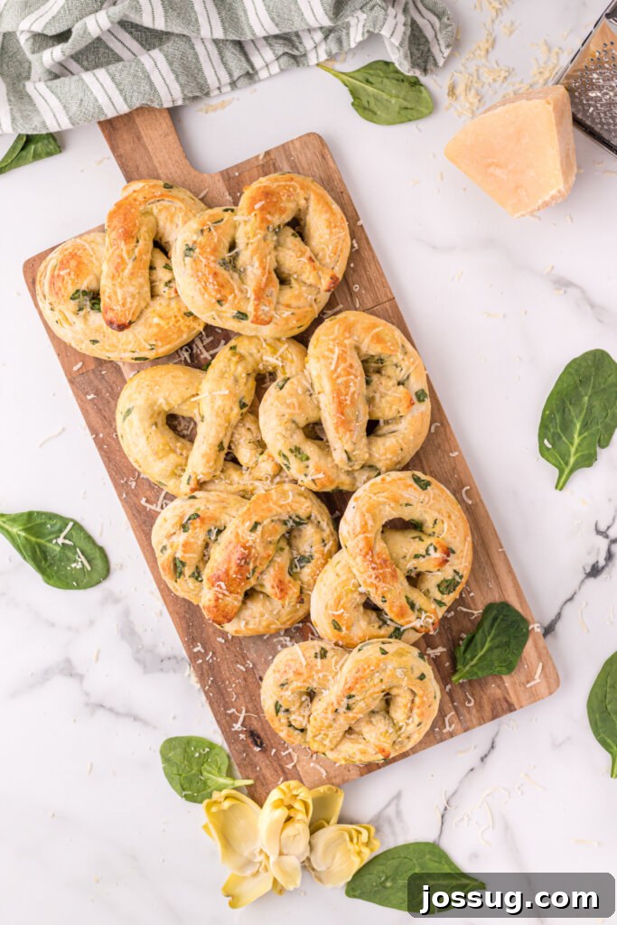 Savory Spinach Artichoke Pretzels 3 Spinach Artichoke Pretzels arranged on a rustic wooden cutting board