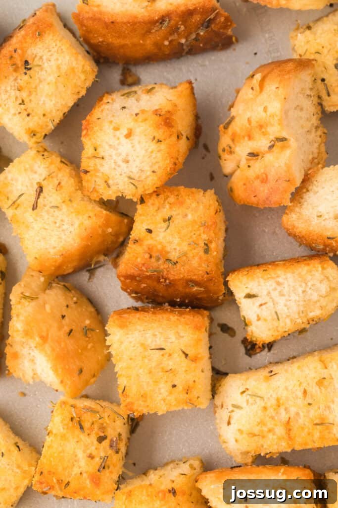 Golden Garlic Parmesan Croutons 4 Close-up view of golden brown homemade garlic parmesan croutons piled on a baking sheet, showcasing their crispy texture.