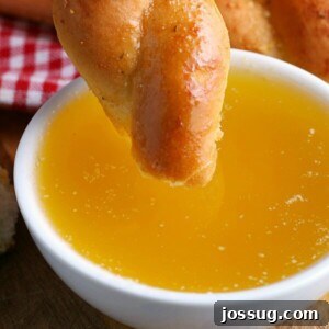 Homemade Garlic Butter Dipping Sauce A small bowl of golden garlic butter dipping sauce with pizza in the background.