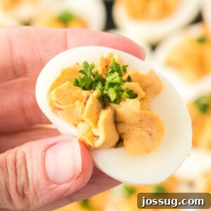 Smoky Chipotle Deviled Eggs 7 closeup of hand holding chipotle deviled egg
