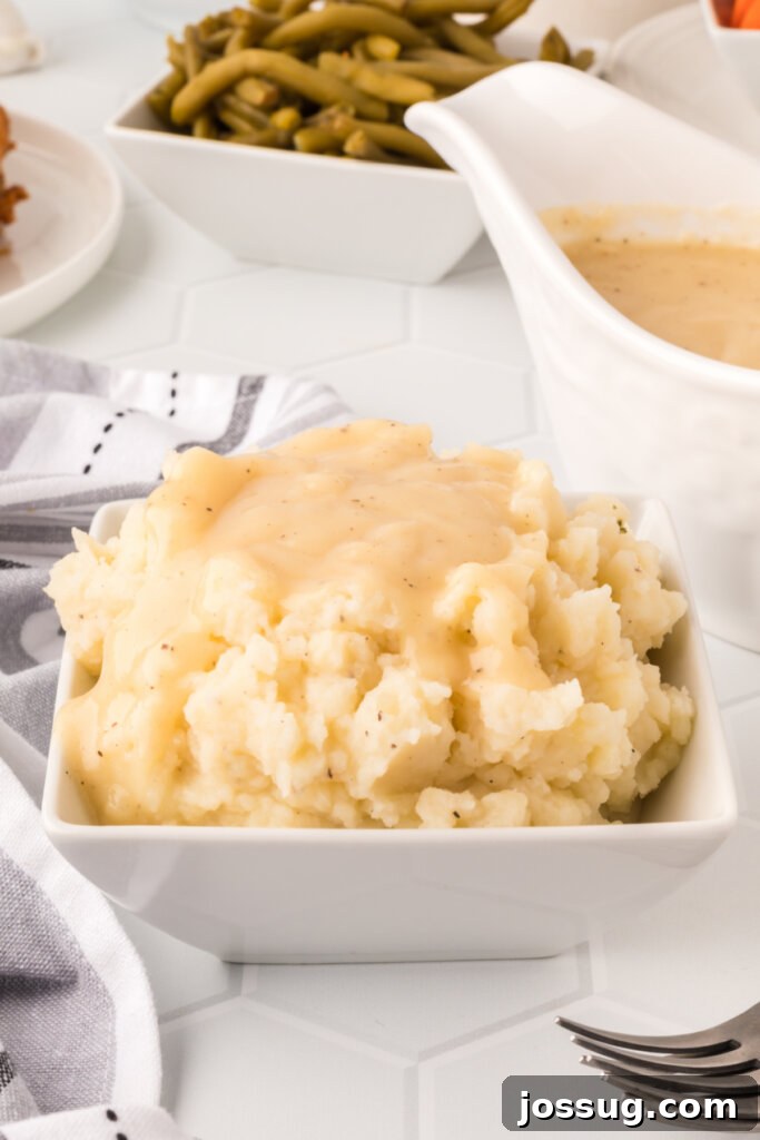 Mastering the Art of Gravy 3 A generous serving of creamy mashed potatoes topped with an ample amount of golden-brown gravy, ready to be served.