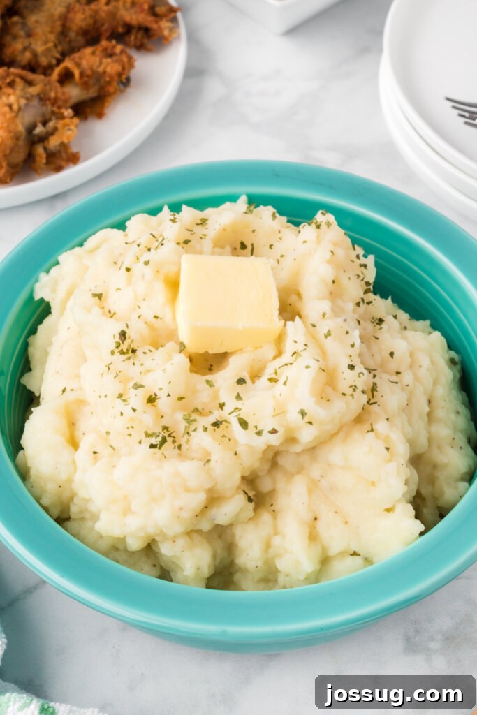 fluffy mashed potatoes topped with butter in an aqua colored bowl