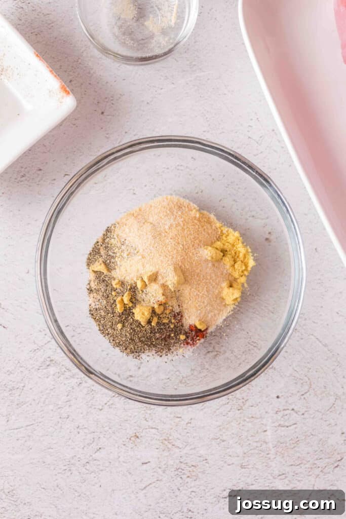 Close-up of seasoning mix in a glass bowl showing layers of spices before mixing