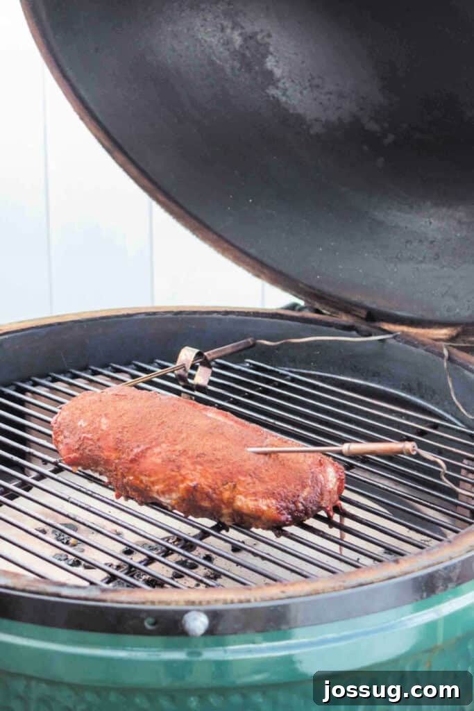 Smoked pork tenderloin halfway through cooking on a ceramic grill