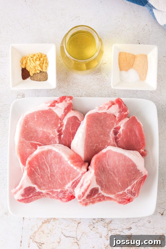 Effortlessly Delicious Smoked Pork Chops 3 Raw bone-in pork chops neatly arranged on a white plate, surrounded by small bowls of seasoning and a bottle of olive oil, ready for preparation.