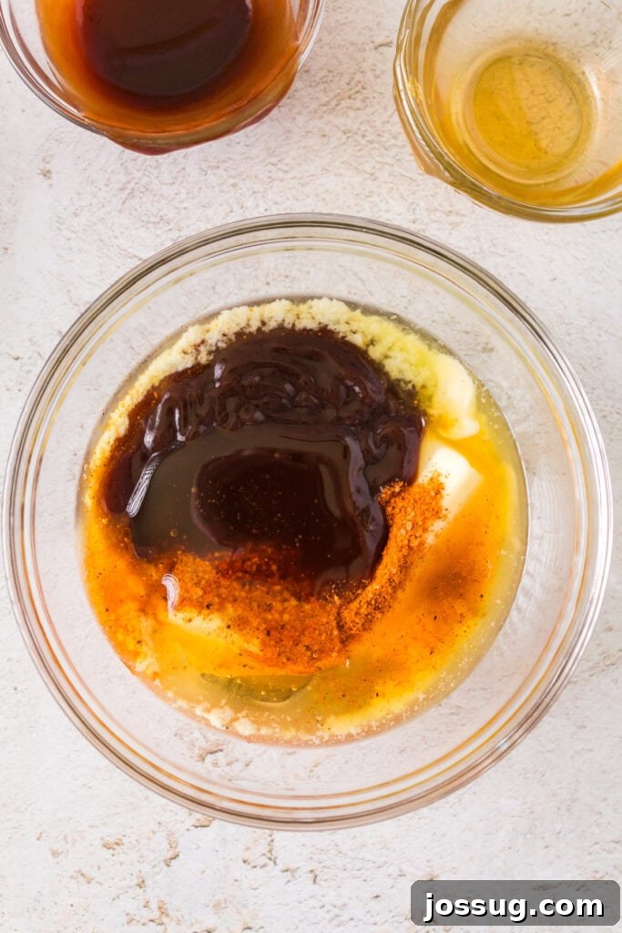 Ingredients for the BBQ sauce mixture in a glass bowl, including butter, BBQ sauce, and honey