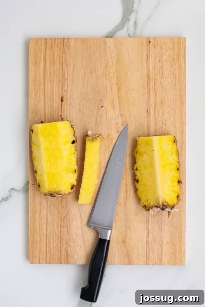 Knife removing the core from pineapple halves on cutting board