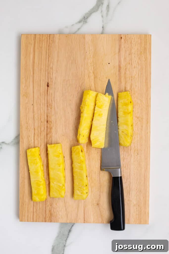 Pineapple sliced into spears on a wooden cutting board