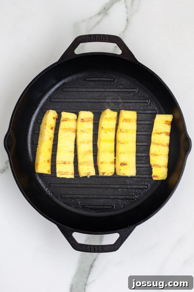 Pineapple spears arranged on a cast iron grill pan with visible grill marks
