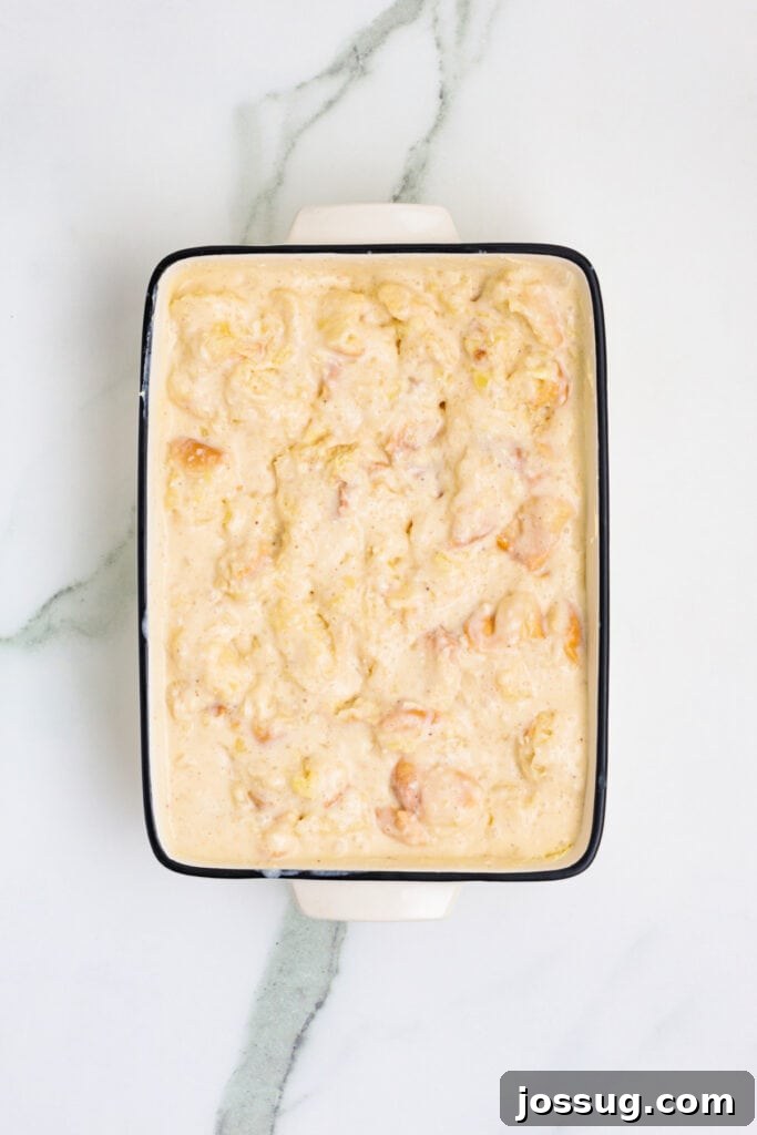 Caribbean Piña Pudding Bake 6 The bread pudding mixture, with torn bread fully soaked in the creamy Piña Colada inspired custard, sitting in a white baking dish just before it's placed into the oven.