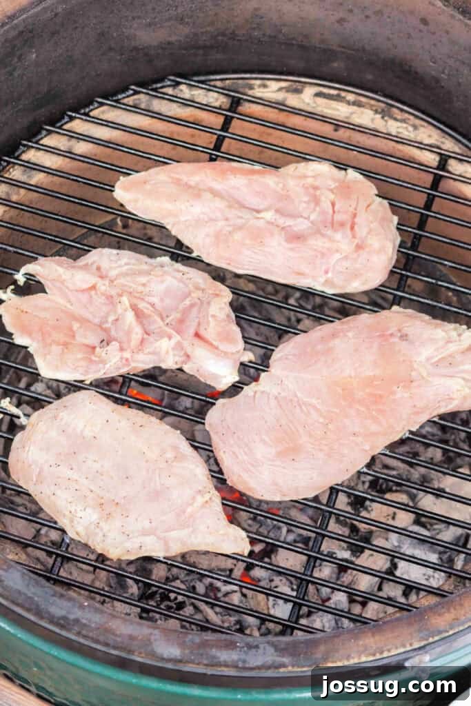 Raw chicken breasts placed on a hot grill over coals