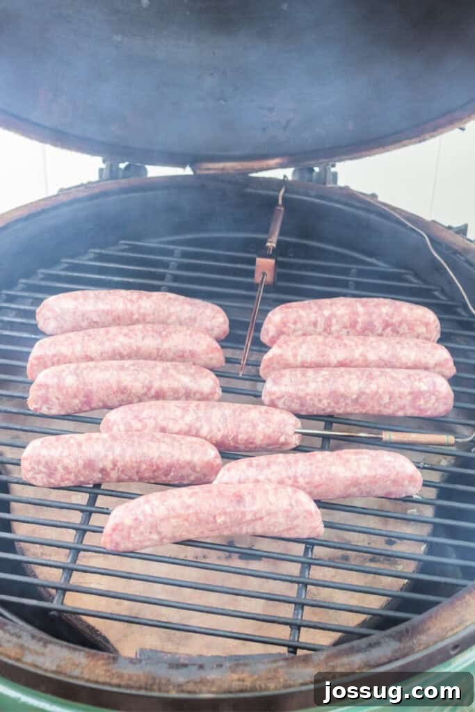 Bratwursts carefully placed on the grill grates inside a smoker, with subtle smoke beginning to rise.