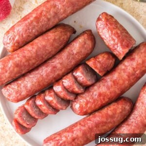 Overhead view of whole and sliced smoked bratwursts arranged on a white plate, ready to be enjoyed.