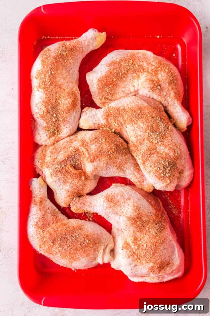 Succulent Smoked Chicken Legs 4 Chicken quarters generously coated in dry rub seasoning, placed in a red tray, ready to go into the smoker.