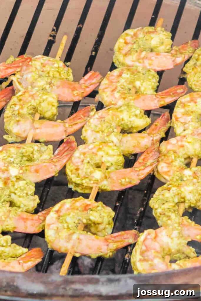 Zesty Grilled Pesto Shrimp 7 Close-up of grilled pesto shrimp cooking on the grill, turning pink and opaque.