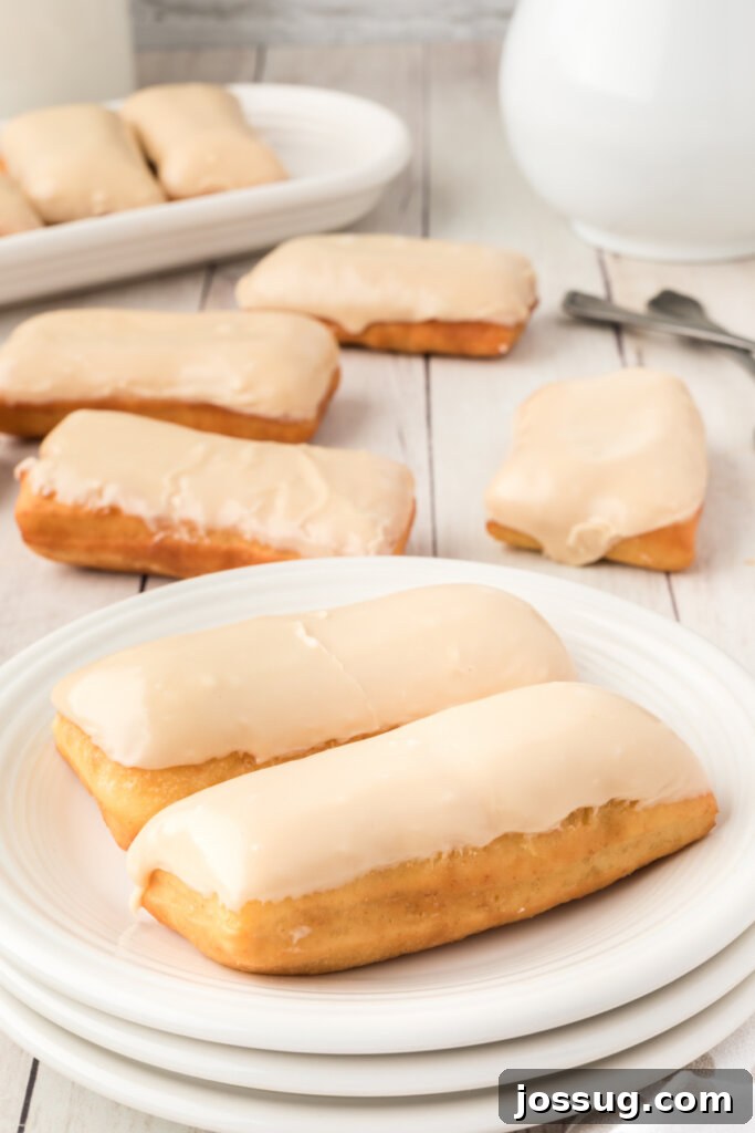 Golden Maple Treats 3 Two freshly glazed maple bars presented on a white plate, showcasing their inviting texture and rich topping.