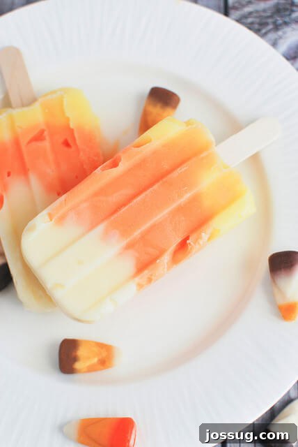 Vibrant Candy Corn Pudding Pops on a white plate, showing their distinct tri-color layers.